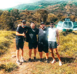 4 men standing in front of a helicopter in a green field medellin heliopter tour