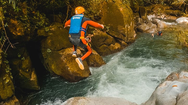 Person jumping into a creek from a rock