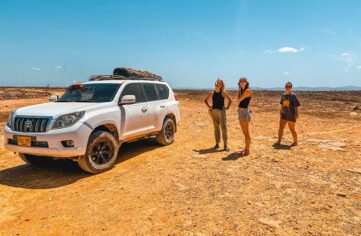 Girls standing next to an SUV in the desert